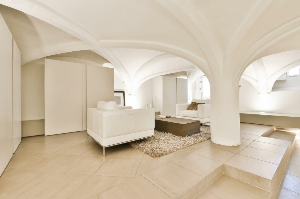 Avant après transformation d'une cave sombre et humide en une pièce de vie habitable et chaleureuse, illustrant le gain de surface.