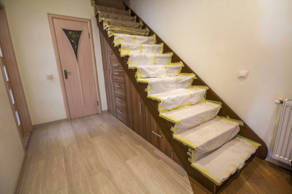 intérieur d'une maison avec escalier en chêne recouvert d'une bâche de protection pendant les travaux de rénovation. Maison moderne avec escalier.