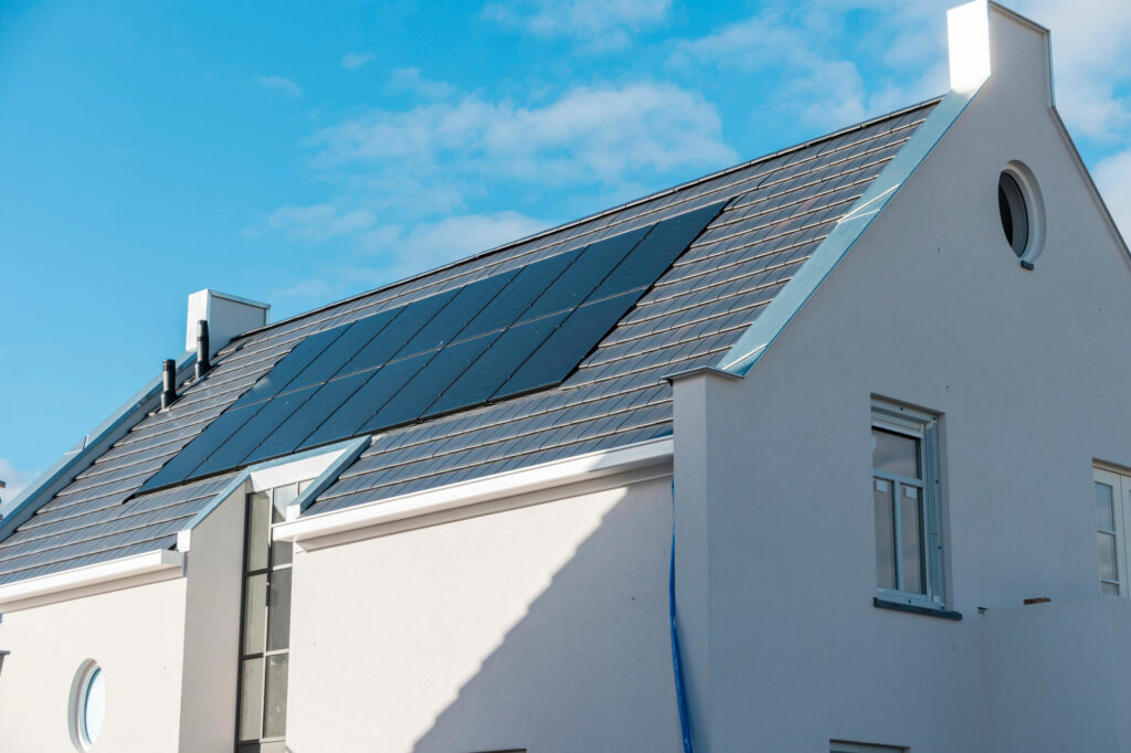 Vue d'une toiture de maison individuelle équipée de panneaux solaires photovoltaïques intégrés, valorisant la production d'énergie décarbonée sur site