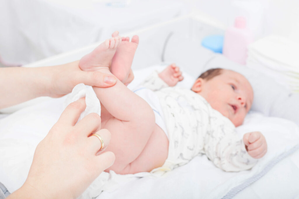 Parent appliquant la règle de la main continue sur une commode à langer sécurisée avec rangements verticaux intégrés.