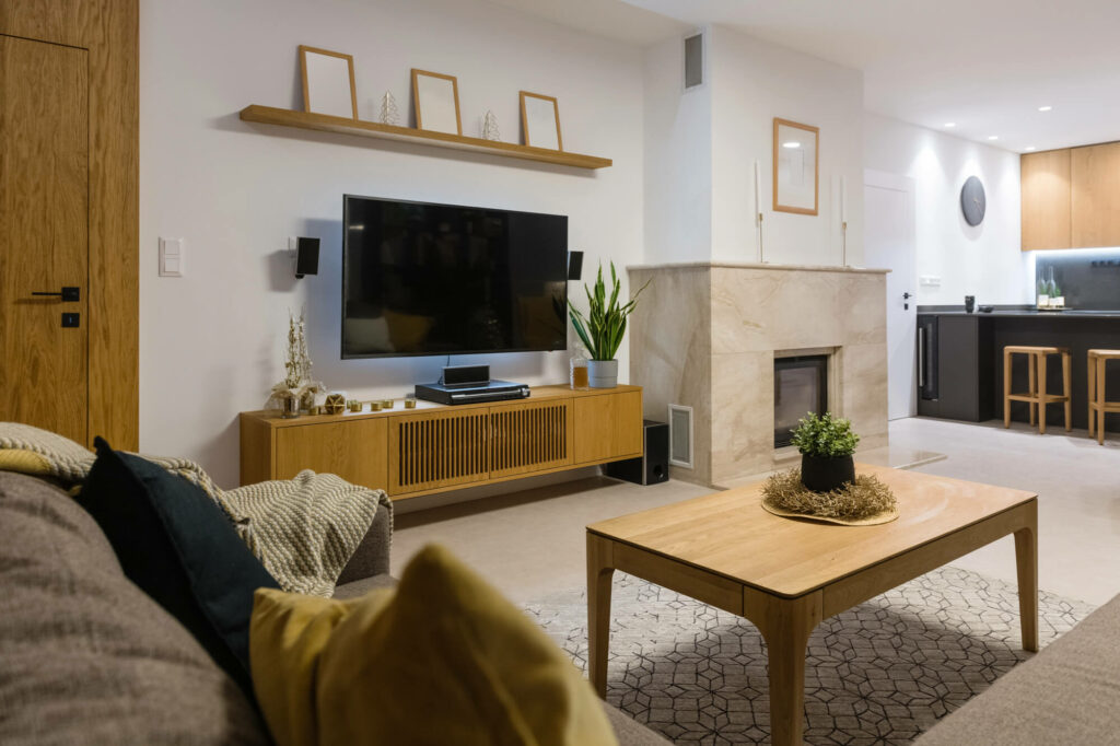 Décoration murale asymétrique avec cadres anti-reflet et plantes pour habiller un meuble TV cheminée.