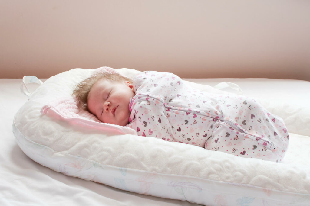 Nourrisson dormant en toute sécurité dans une gigoteuse adaptée à la température, dans un lit à barreaux sans peluche ni tour de lit.